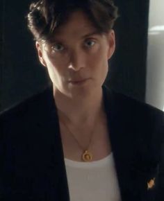 a woman in a white shirt and black jacket looking at the camera with an intense look on her face