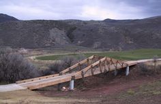 a wooden bridge over a dirt road in the mountains