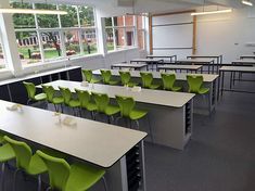 an empty classroom with green chairs and desks