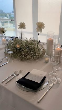 the table is set with silverware, candles and flowers in vases on it