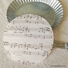 a paper plate with sheet music on it next to a cookie tin cupcake liner