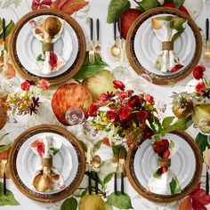 the table is set with white plates, silverware and autumn leaves on it's wallpaper