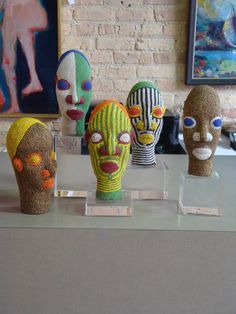 five knitted masks sitting on top of a glass table in front of a brick wall