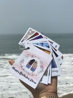 someone holding up some cards with the ocean in the background