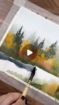 someone is painting an image with watercolors on paper and using a paintbrush