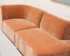 an orange couch sitting on top of a white floor next to a wall with a window