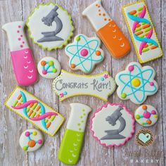 decorated cookies are arranged in the shape of science related items on a wooden table with text that reads congrats rni