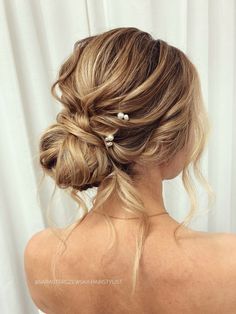 a woman with blonde hair in a low bun and two pearls on the back of her head