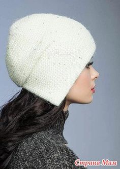 a woman with long black hair wearing a white knitted beanie hat and looking off to the side