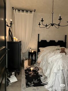 a bedroom with a bed, dresser and chandelier hanging from the ceiling above it