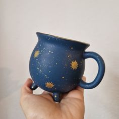 a hand holding a blue mug with stars painted on it