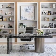 an office with white shelving and black leather chair in front of a marble topped desk