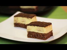 two pieces of cake sitting on top of a white plate in front of a green tablecloth