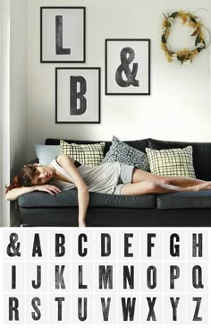 a woman laying on top of a couch next to a black and white alphabet poster