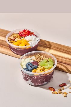 two bowls filled with different types of food on top of a wooden tray next to a cutting board