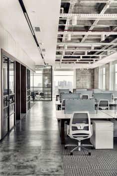 an empty office with lots of desks and chairs in front of large windows overlooking the city