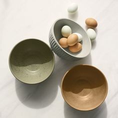 three bowls with eggs in them sitting on a table