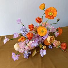 a vase filled with lots of different colored flowers on top of a brown table cloth