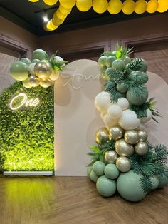 balloons and greenery on display in front of a one - sided sign at an event