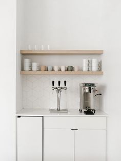 the coffee maker is sitting on top of the white cupboards in the kitchen area