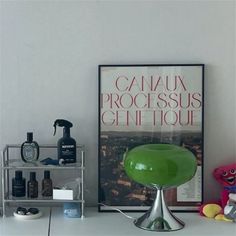 a green lamp sitting on top of a table next to a poster and other items