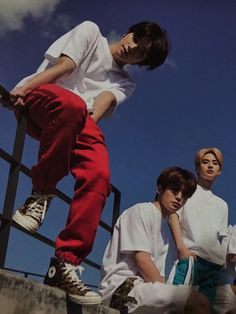 three young men sitting and standing on top of steps with their feet in the air