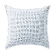 a white pillow with fraying on the front and back, against a white background