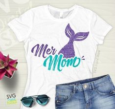 a t - shirt with the words mermaid on it next to some sunglasses and flowers