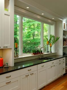 a kitchen filled with lots of counter top space next to a large window covered in green trees