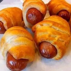 four hotdogs wrapped in bread sitting on top of a table