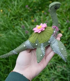 a hand holding a small stuffed animal with a flower on it