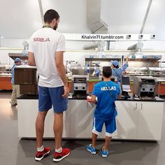 two boys are standing in front of a counter with food on it and one boy is wearing blue shorts