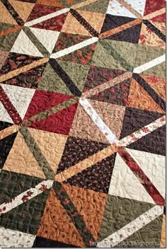 a quilted table topper with many different colors and patterns on the fabric,