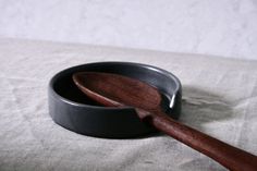 a wooden spoon sitting in a black bowl on top of a white cloth covered table