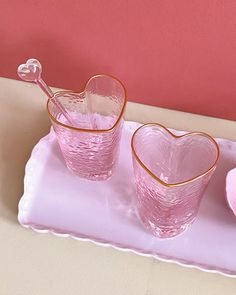 two heart shaped glasses on a pink tray