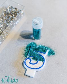 a cake shaped like the number five with blue icing and sprinkles