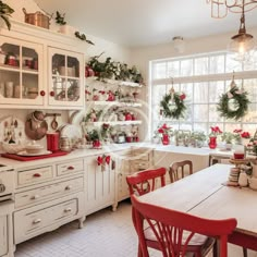 a kitchen filled with lots of white cabinets and christmas decorations on the windowsills