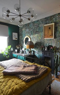 a bedroom with green wallpaper and a large mirror on the dresser next to it