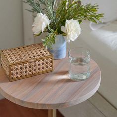 a vase with white flowers sitting on top of a table next to a small box