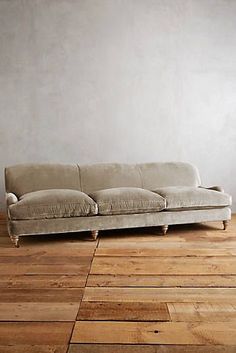 a couch sitting on top of a wooden floor next to a white wall and window