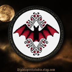 a cross - stitch bat hanging on a wall with the moon in the background