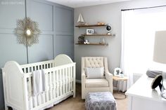 a baby's room with a white crib, chair and shelf on the wall