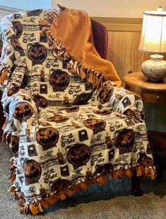 a chair with a blanket on top of it in front of a table and lamp