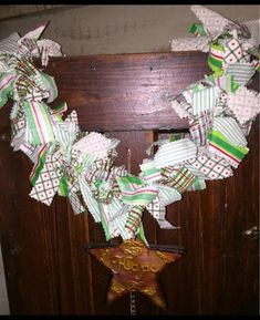 a wreath is hanging on a door with ribbons around it and an ornament in the shape of a star