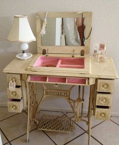 an antique sewing table with a pink sink and mirror on it's top, in front of a white wall