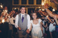 a bride and groom holding sparklers in front of their wedding guests at the reception