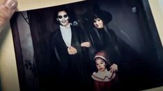 a person holding up a photo with two people dressed as the addams on it