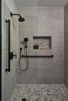 a walk in shower sitting next to a tiled wall and floor covered in gray tiles