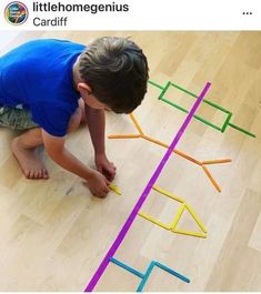 a young boy is playing with colored sticks on the floor