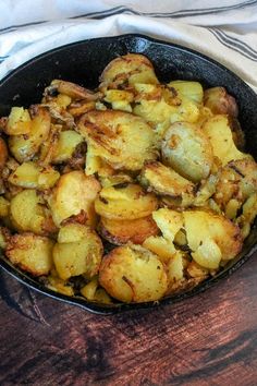 a skillet filled with potatoes on top of a wooden table